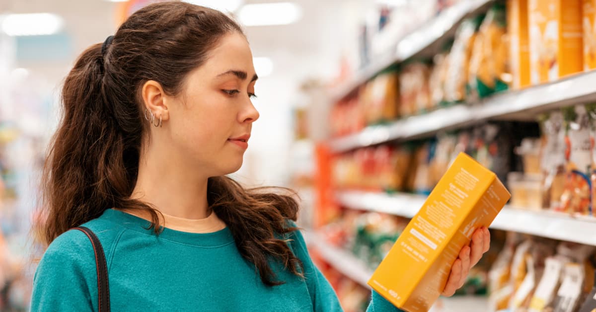 Young woman reading the nutrition label on a food package