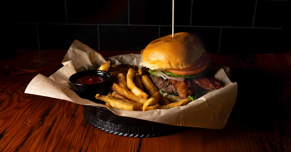 A delicious burger with fries and a side of ketchup on a dark wood table