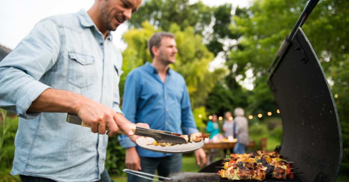 two men at a backyard bbq grilling chicken skewers