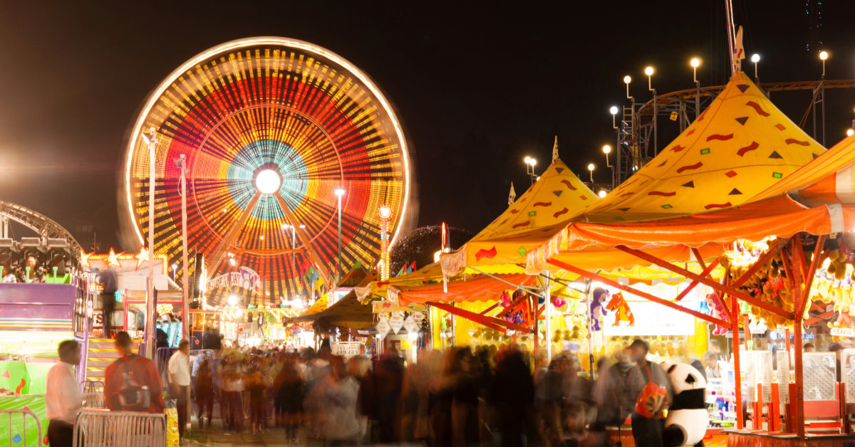 the main strip of a state fair ground with tents and a ferris wheel 