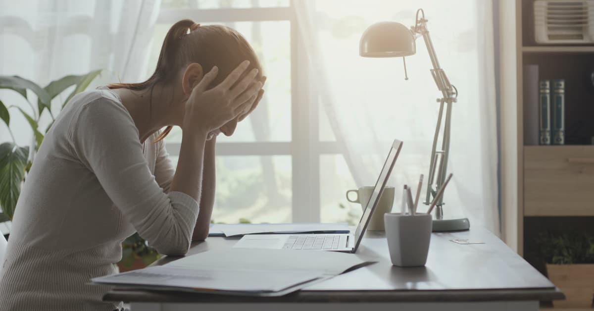 woman sitting a work desk with her face in her hands from skipping lunch