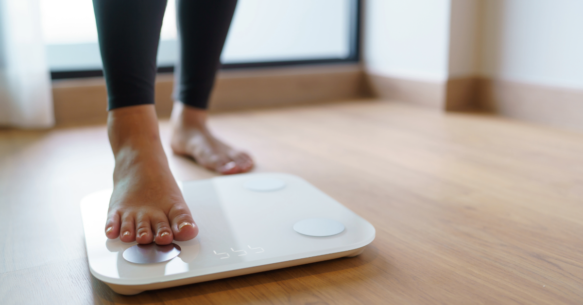 woman in leggings stepping on a white bathroom scale