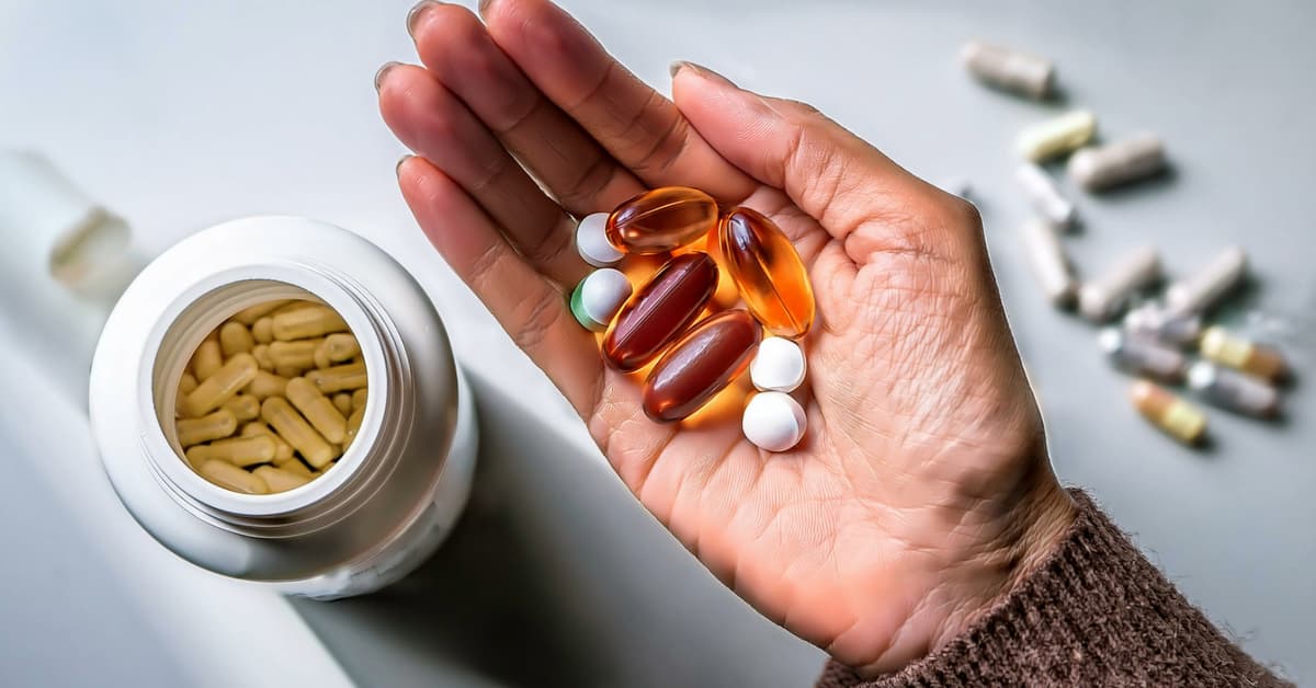 a woman's hand full of a variety of daily supplements 