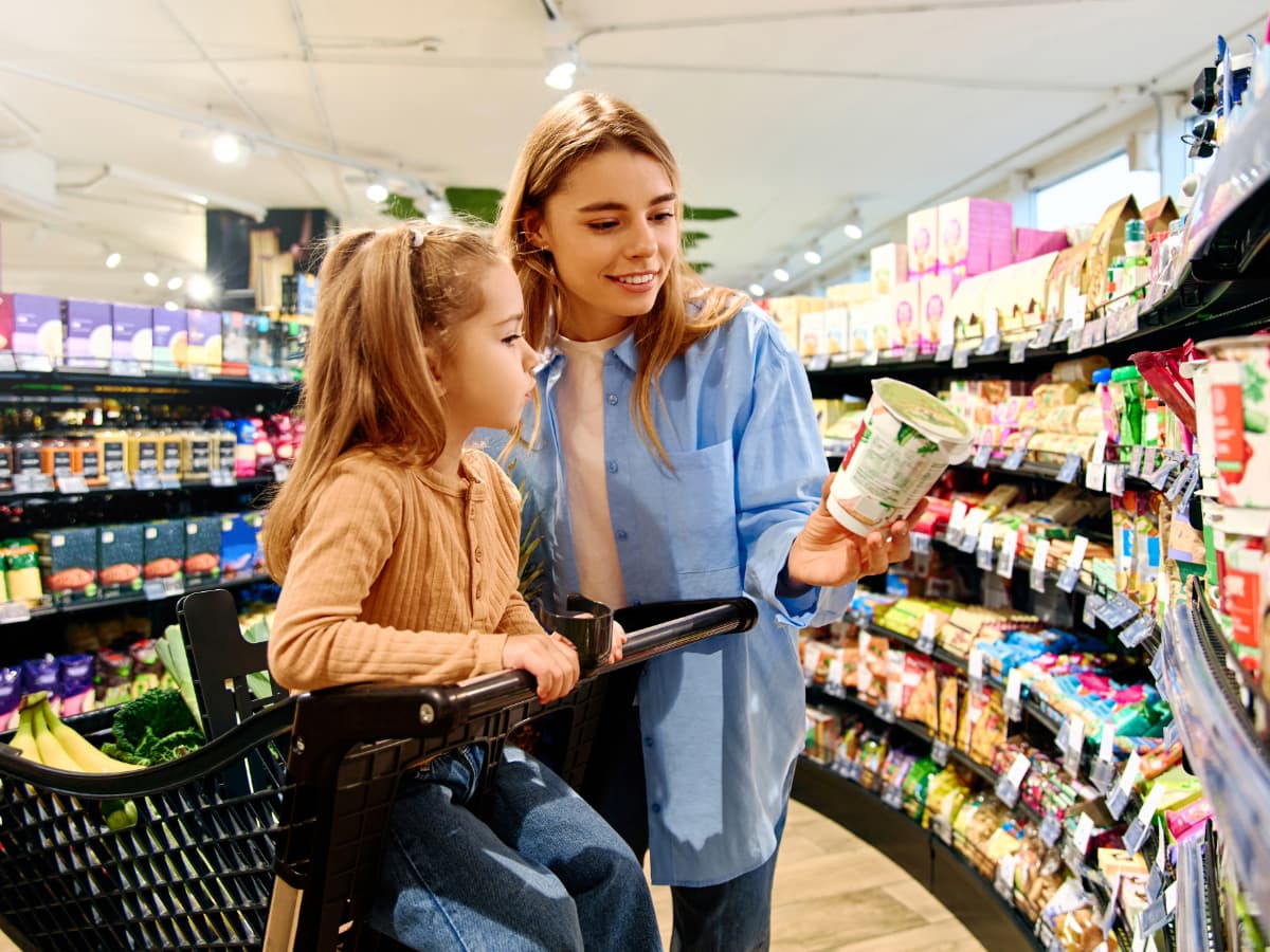 Woman reading a nutrition label to her child at the grocery store 