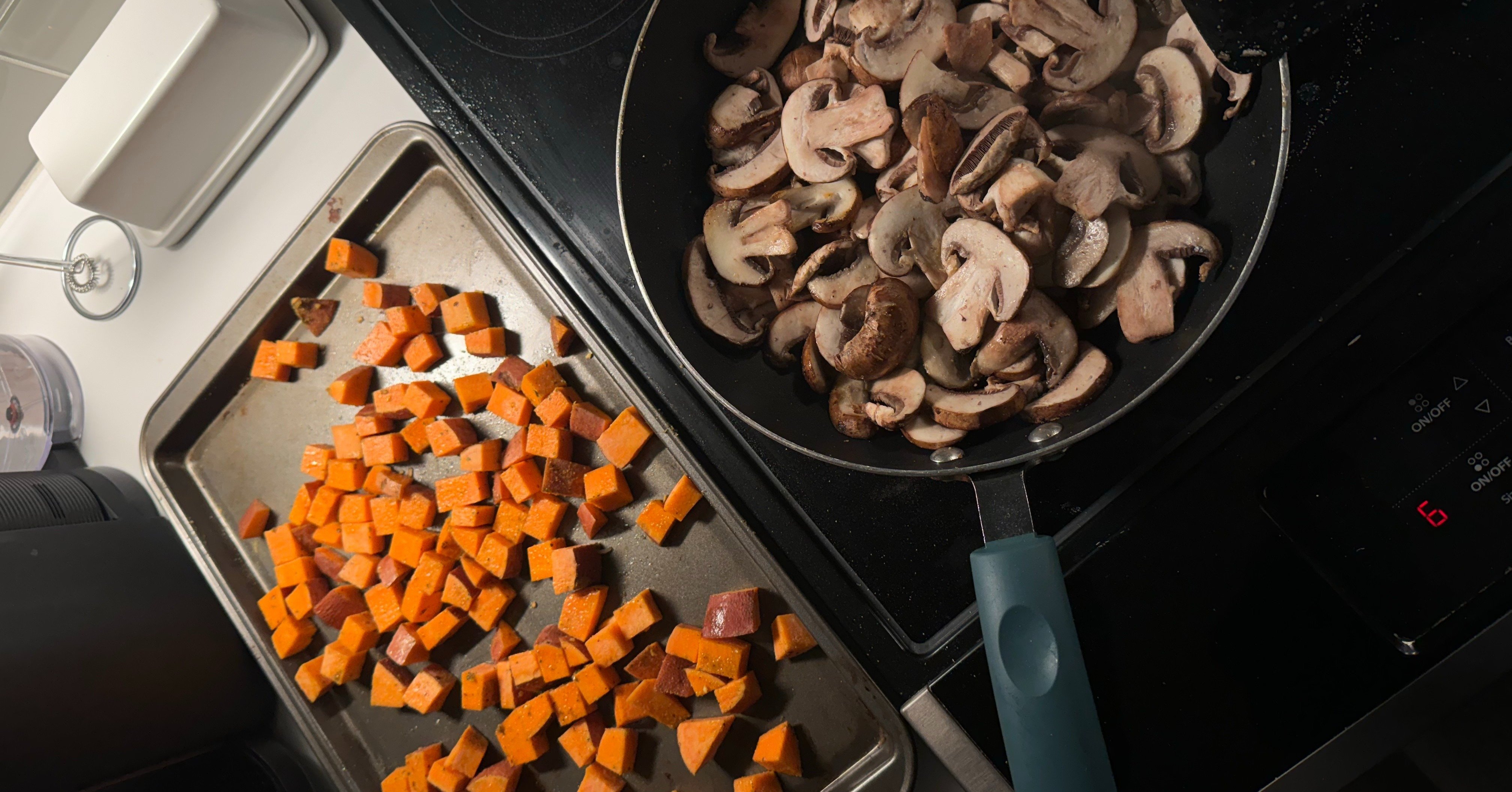 diced sweet potatoes on a baking sheet and sliced mushrooms in a blue saucepan cooking on an electric stovetop
